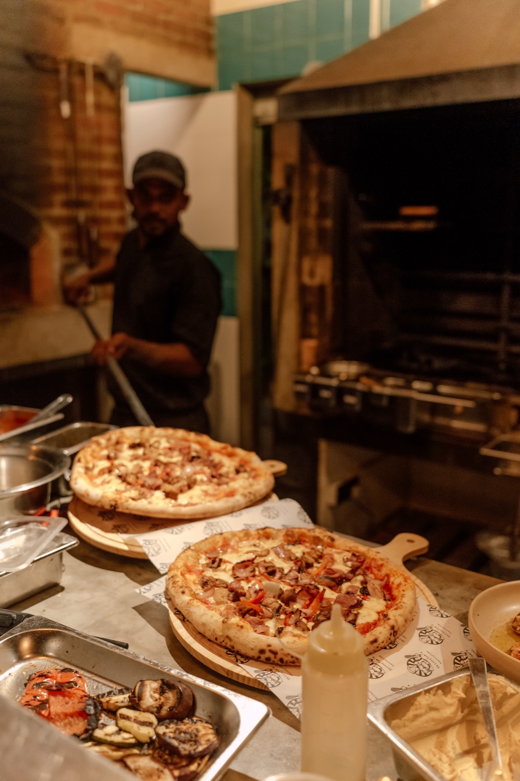 Chef preparing wood-fired sourdough pizza at the stone oven